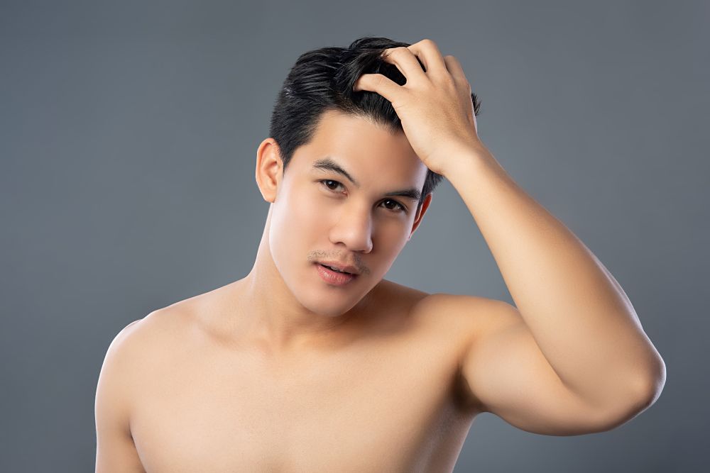 ผู้ชายเสยผมอย่างมั่นใจหลังได้รับการสักไรผม